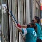 Un par de mujeres trabajan limpiando los cristales de un edificio en Paseo de la Reforma.