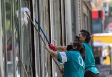 Un par de mujeres trabajan limpiando los cristales de un edificio en Paseo de la Reforma.
