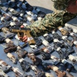 A soldier displays seized handguns