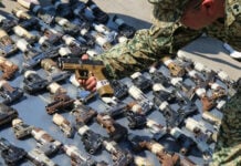 A soldier displays seized handguns