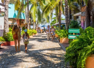 Tourists stroll beneath palm trees on the streets of Sayulita, Mexico