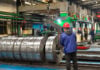 Chinese mill workers prepare hot-rolled steel coils.