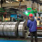 Chinese mill workers prepare hot-rolled steel coils.