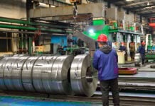 Chinese mill workers prepare hot-rolled steel coils.