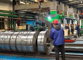 Chinese mill workers prepare hot-rolled steel coils.