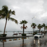 A car drives down the flooded ocean-front malecón of La Paz in 2022 after Hurricane Kay