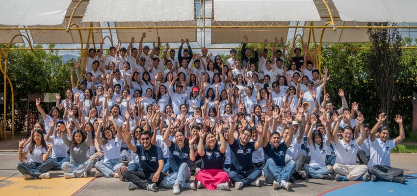 A large group of university students supported by the Jóvenes Adelante non-profit celebrate with raised hands during one of the many community-driven San Miguel events in Guanajuato, Mexico.