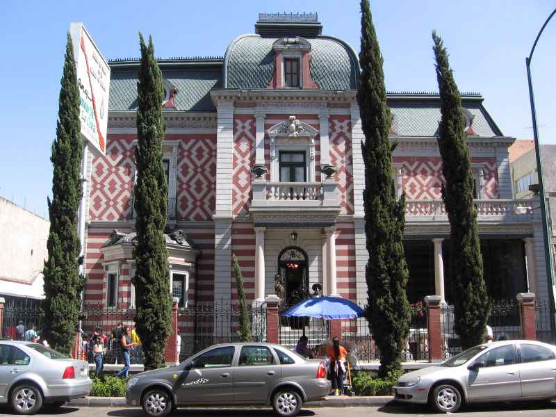 Mexico City Wax Museum's Art Nouveau facade with pink and white cantera stone and tiling done in stripes and in Arab-style mosaic diamond patterns. The museum is right in front of a Mexico City street.