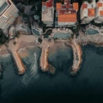 Aerial view of a part of the coastline of Puerto Vallarta, featuring beachfront homes in bright orange and white and pools of various shapes.