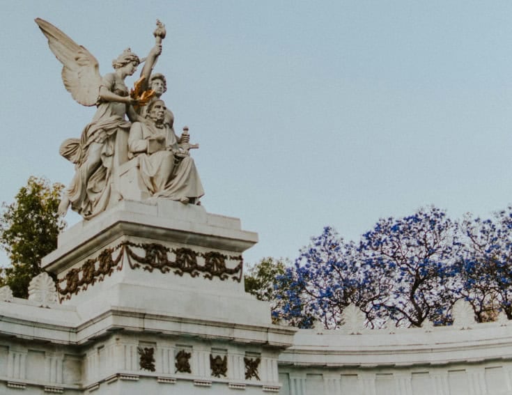 Side view of the Monument to Mexican President Benito Juarez. The statue shows Juarez seated, being given a golden laurel wreath by Greek goddesses