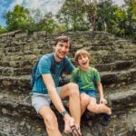 A dad and his middle schooler son take a selfie at a Maya pyramid in Mexico
