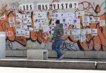 A man walks by a wall of posters of missing people in Mexico City