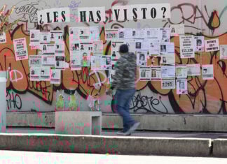 A man walks by a wall of posters of missing people in Mexico City
