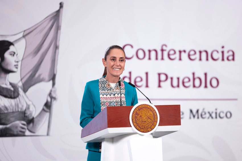 Mexican president Claudia Sheinbaum at a press conference, standing at a podium with a banner-sized wall behind her that features the logo of her administration, a young Indigenous woman holding the Mexican flag, and, in Spanish, the words "The People's (Press) Conference.