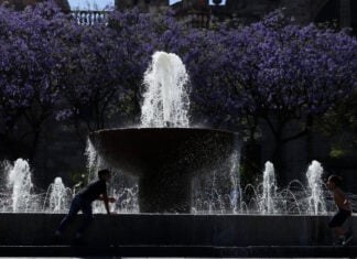 Children in silhouette playing on a bright day by a fountain in the historic center of Guadalajara, Mexico.