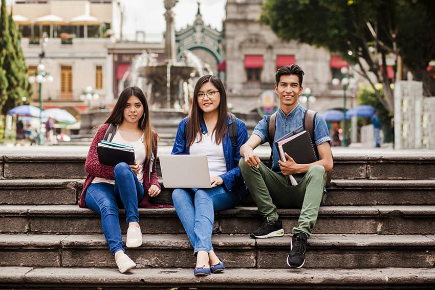 Students sit on steps in a street scene from Mexico City