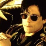 Benecio del Toro in dark aviator sunglasses sitting in a car, in a scene from the film "Traffic."