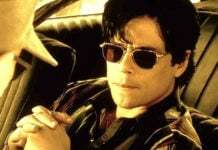 Benecio del Toro in dark aviator sunglasses sitting in a car, in a scene from the film "Traffic."
