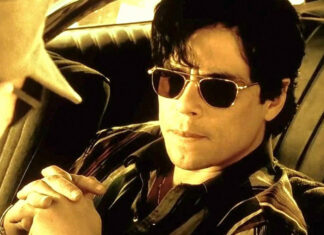 Benecio del Toro in dark aviator sunglasses sitting in a car, in a scene from the film "Traffic."