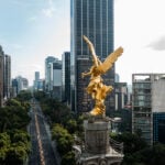 A view over the shoulder of the golden Angel of Independence statue in Mexico City, looking down Paseo de la Reforma