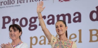 President Sheinbaum waves from the stage of a press conference
