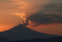 Small clouds of ash from Popocatépetl volcano catch the light of the rising sun