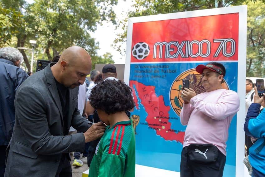 Oscar "El Conejo" Pérez signs a jersey during the unveiling of monumental Panini cards along Mexico City's Reforma Avenue, featuring soccer players who have played key roles in World Cups throughout history. 