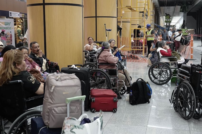 Airport passengers resting on the side of a hallway while construction goes on