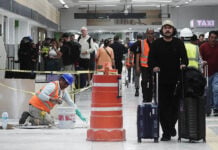 Passengers walk past orange construction cones and a construction worker in Mexico City International Airport (AICM)