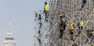 Workers on scaffolding with Mexico City's Torre Latinoamericano in the background