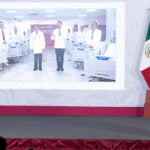 Sheinbaum stands before a podium and views a presentation by her government's Health Ministry