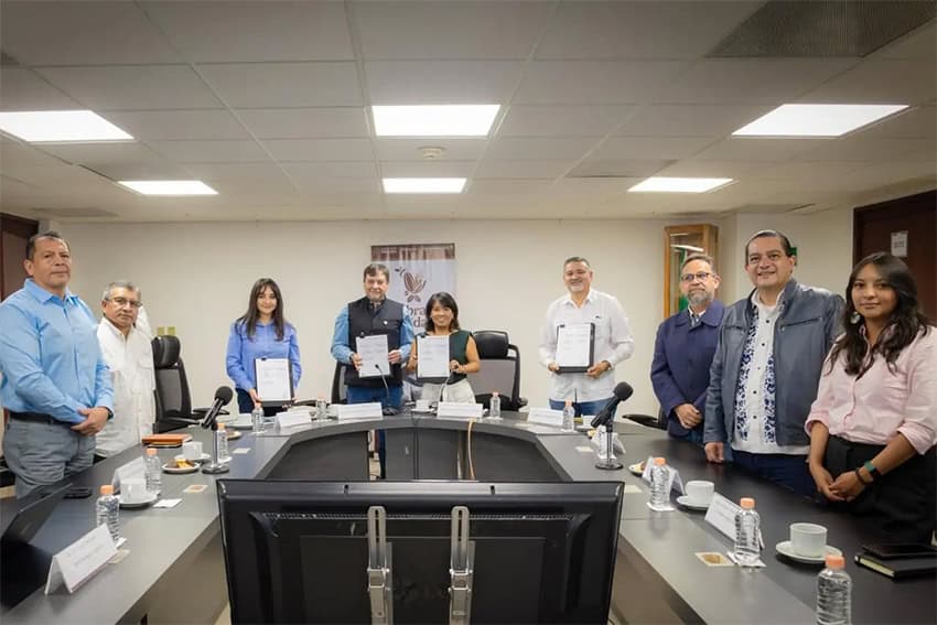 Officials in a board room hold up a signed document for the camera