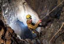 A man rappels down into a cave