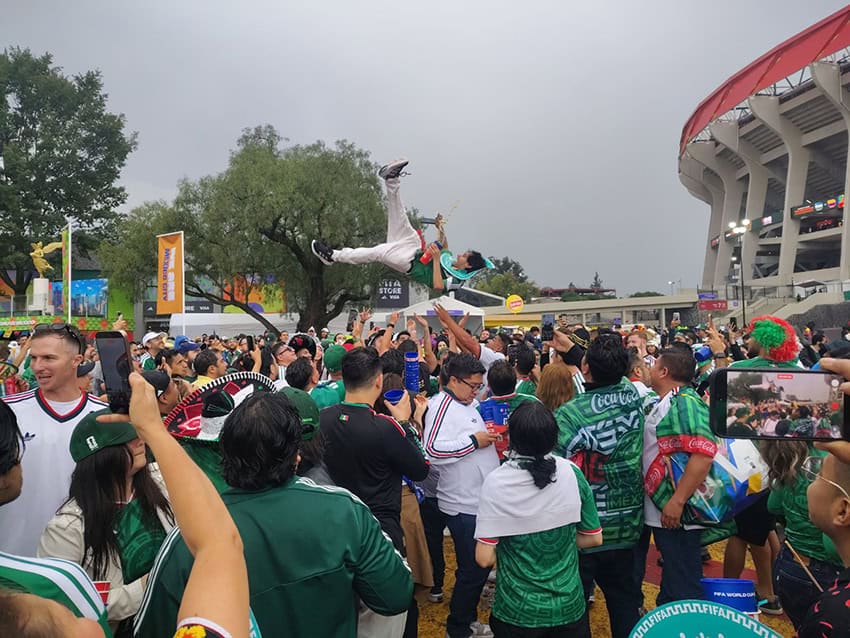 Mexican fans dance and throw someone in the air as they celebrate their team's win outside Mexico City Stadium. 