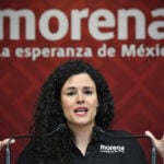 Morena Party President Luisa María Alcalde at a podium in front of a Morena banner