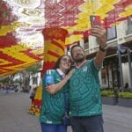 tourist take pictures with Zapopan's woven World Cup canopy