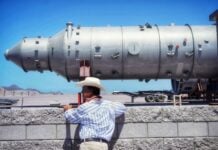 a protester seen looking left with large plant equipment in the background