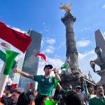 fans blow horns and wave mexican flags below the Angel of Independence monument in Mexico City after Mexico's World Cup win against south africa