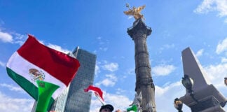 fans blow horns and wave mexican flags below the Angel of Independence monument in Mexico City after Mexico's World Cup win against south africa