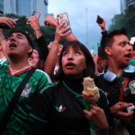 Mexican fans look up at a screen to watch a world cup match