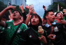 Mexican fans look up at a screen to watch a world cup match