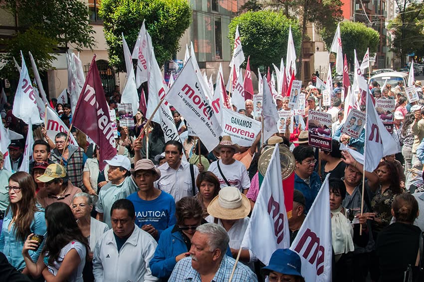 Dozens of Morena party members wave flags at a rally