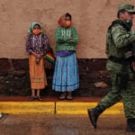 Two women in traditional Rarámuri dress watch as National Guard members patrol the town of Cerocahui in the mountainous region of Chihuahua known as the Sierra Tarahumara.