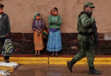 Two women in traditional Rarámuri dress watch as National Guard members patrol the town of Cerocahui in the mountainous region of Chihuahua known as the Sierra Tarahumara.