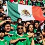 Mexicans giving the saludo civil during the national anthem at a football game