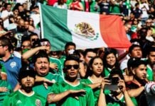 Mexicans giving the saludo civil during the national anthem at a football game