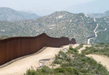 The Mexico-US border wall cuts through an arid mountainous landscape