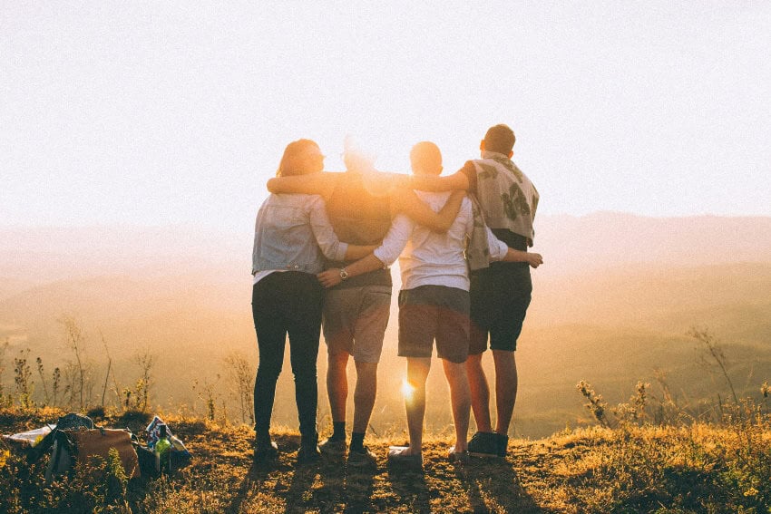 Friends hugging on a sunny hilltop plateau