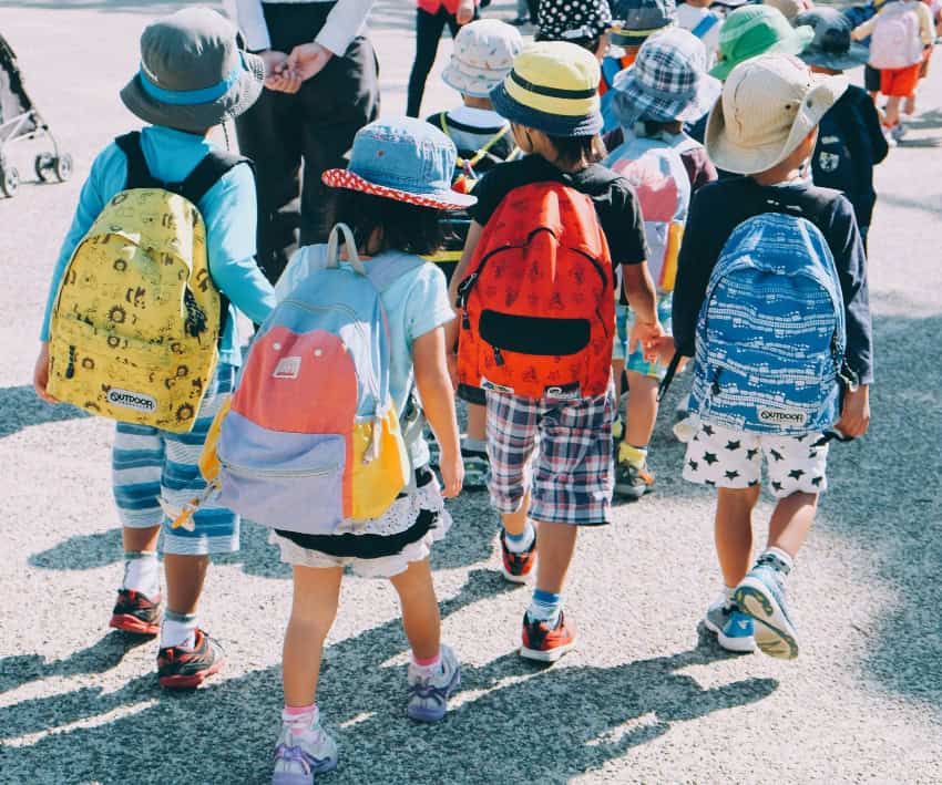 Small children walking to school with their backpacks on