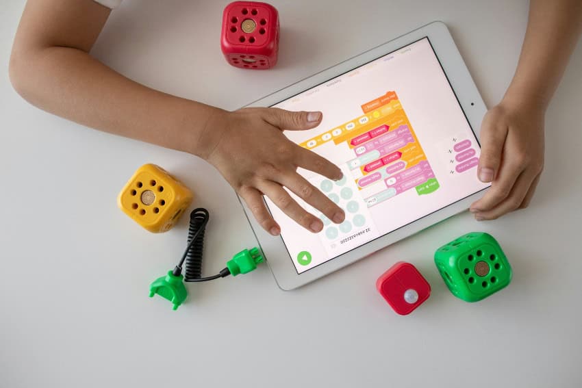 Young child looking at device with toys around it